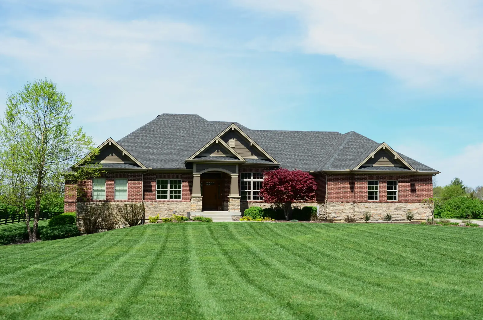 A brick house with a freshly mowed, striped front lawn